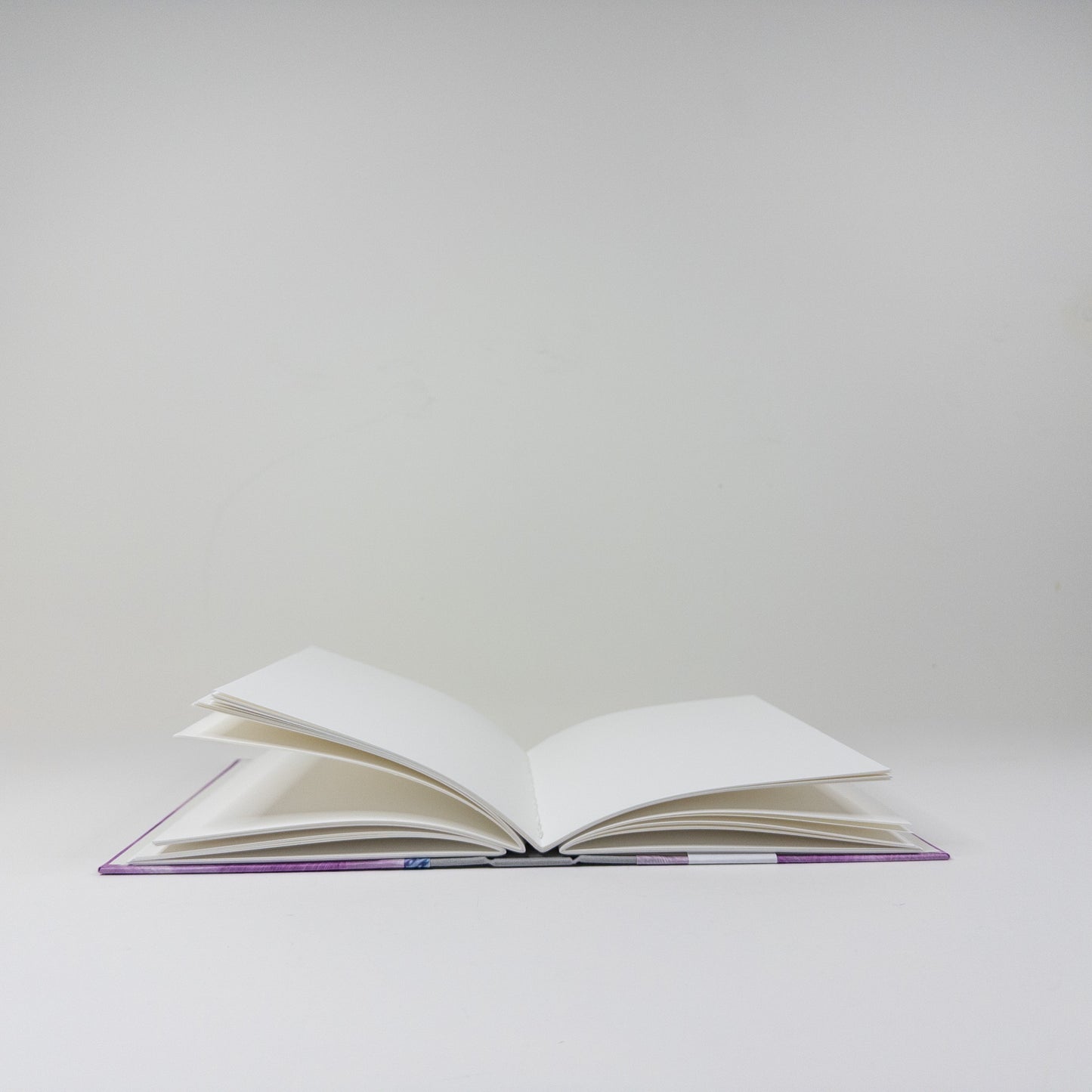 Handmade book standing upright, showing paste paper cover and blank text block