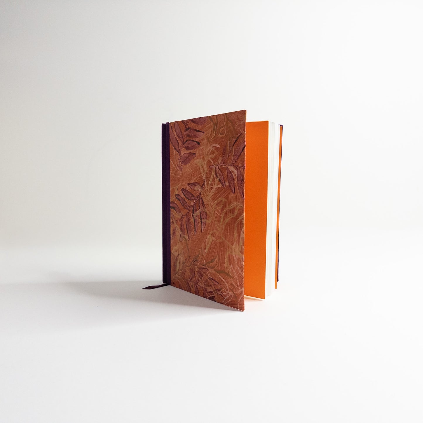 Handmade journal standing upright, showing orange endpapers and blank text block