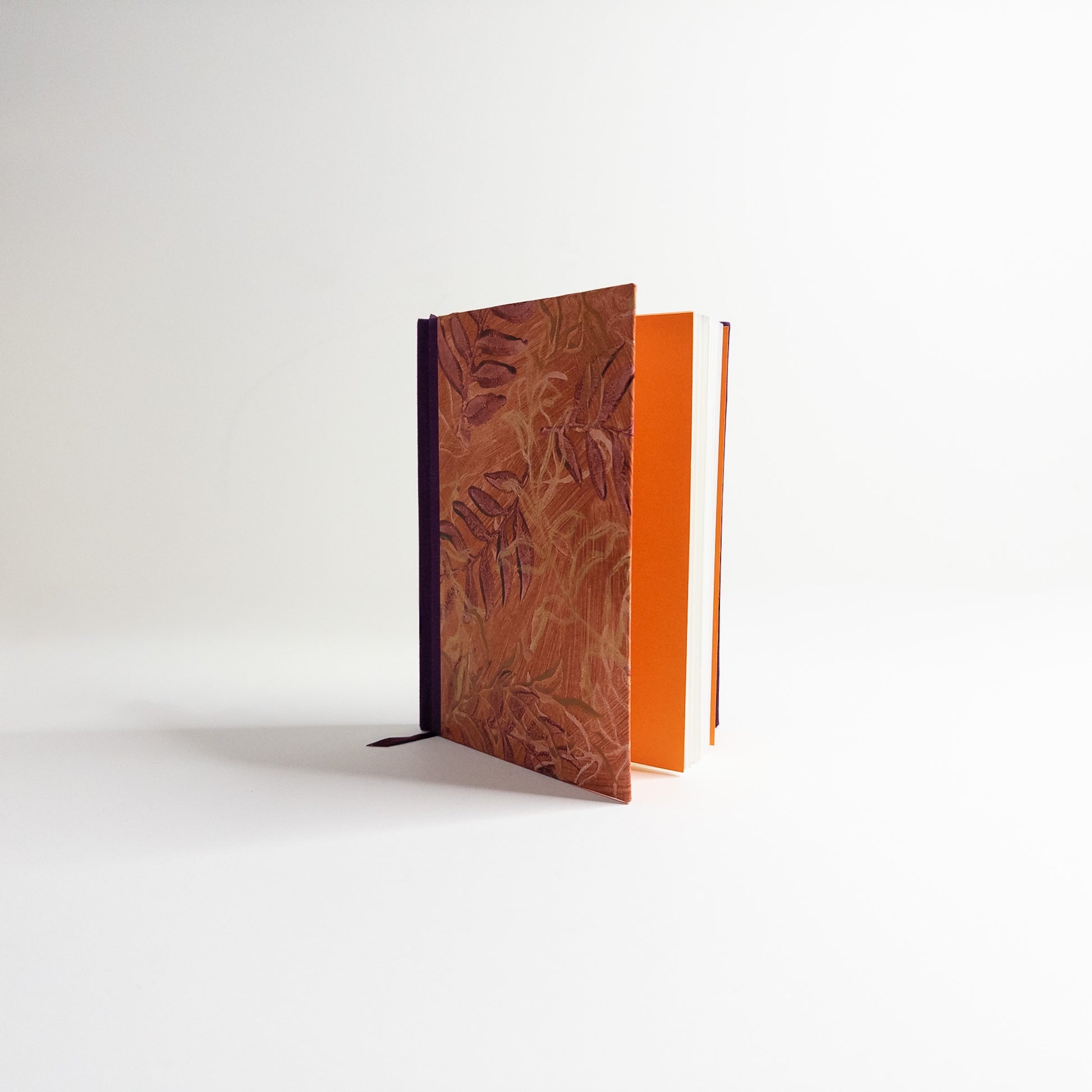 Handmade journal standing upright, showing orange endpapers and blank text block