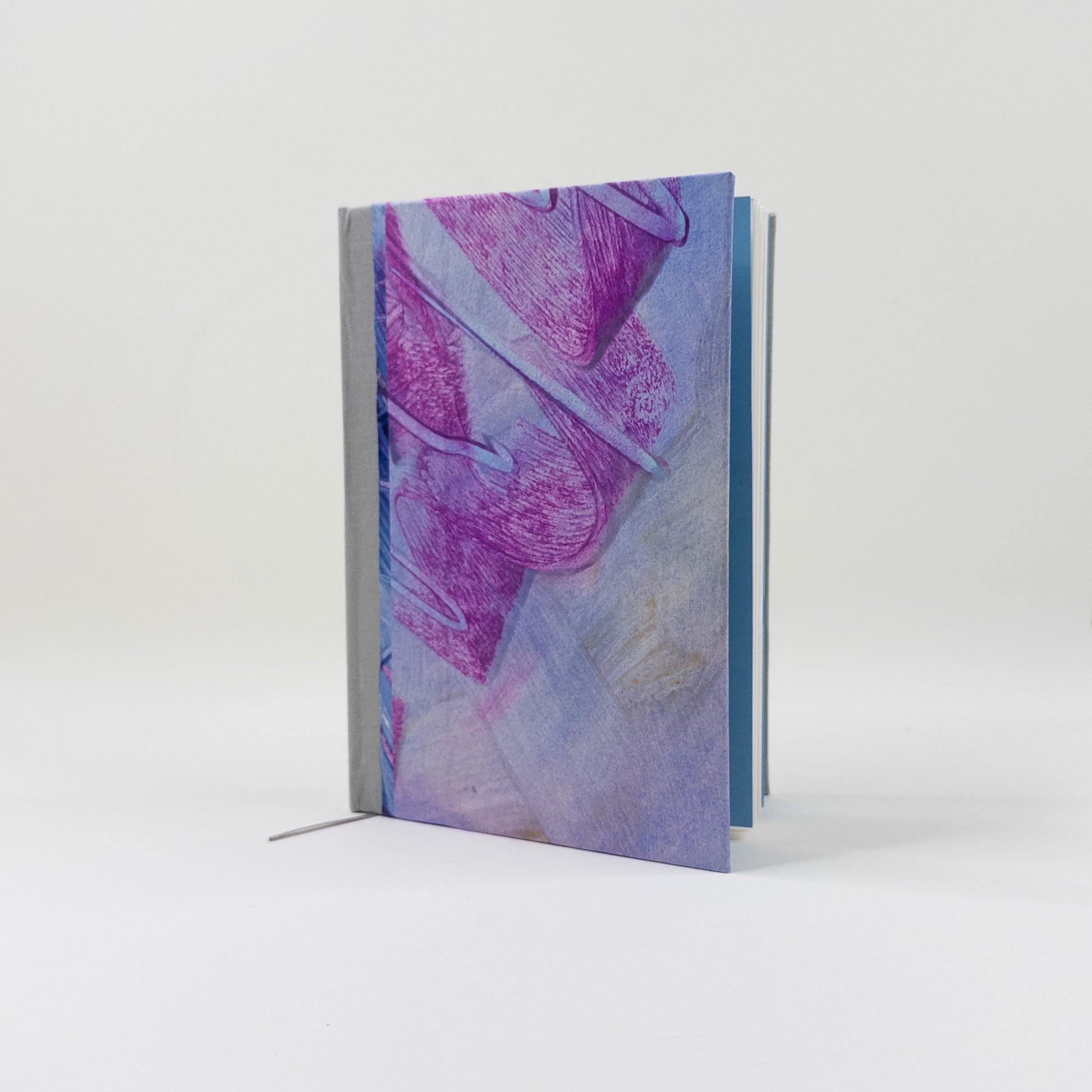 Handmade journal standing upright, showing teal endpapers and blank text block