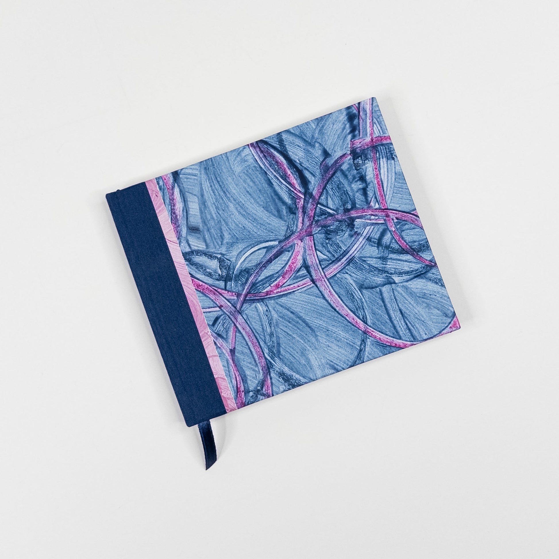 Blue and pink paste paper cover with navy book cloth spine and ribbon marker, hand bound by Patti Paulus