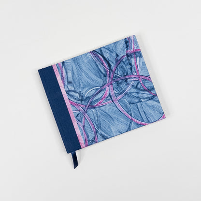 Blue and pink paste paper cover with navy book cloth spine and ribbon marker, hand bound by Patti Paulus
