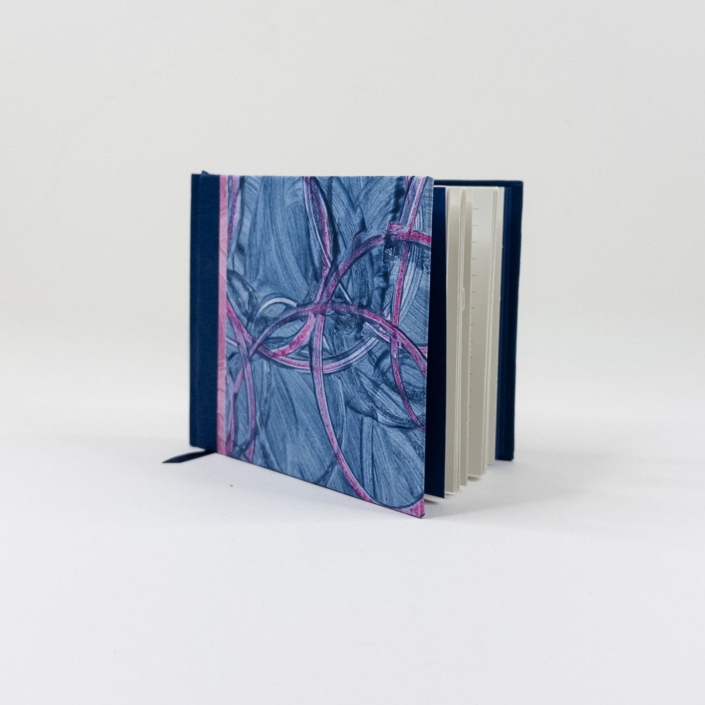 Landscape handmade journal standing upright, showing lined pages and navy ribbon