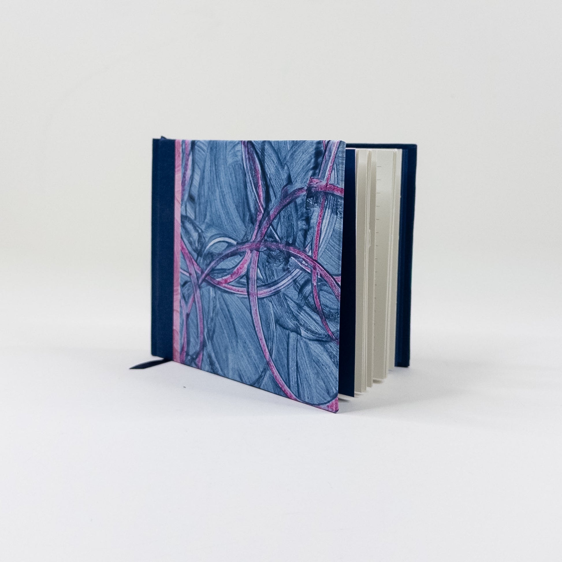 Landscape handmade journal standing upright, showing lined pages and navy ribbon