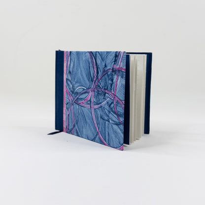 Landscape handmade journal standing upright, showing lined pages and navy ribbon