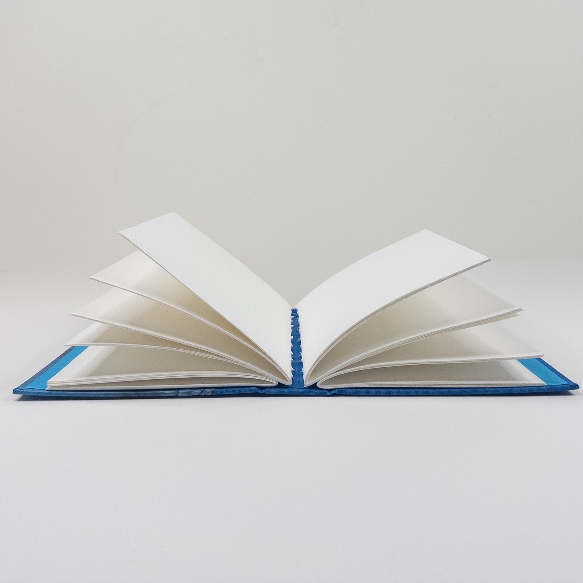 Handmade book standing upright, showing paste paper cover and blank text block