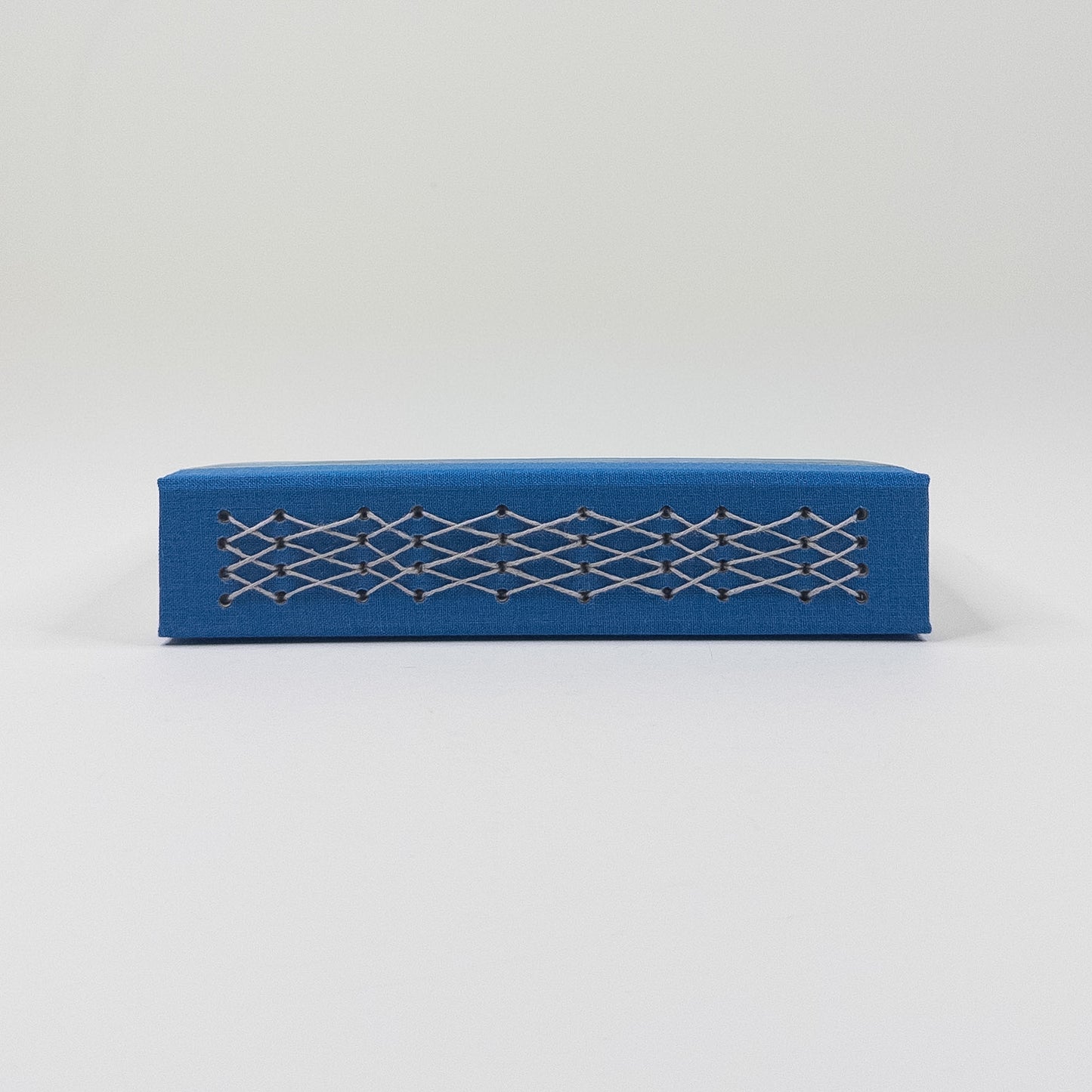 Blue linen spine crossed with a pale lattice of linen thread stitching